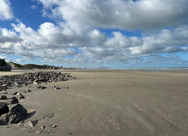 Vast sandy expanse of Dunkirk beach with a cloudy blue sky