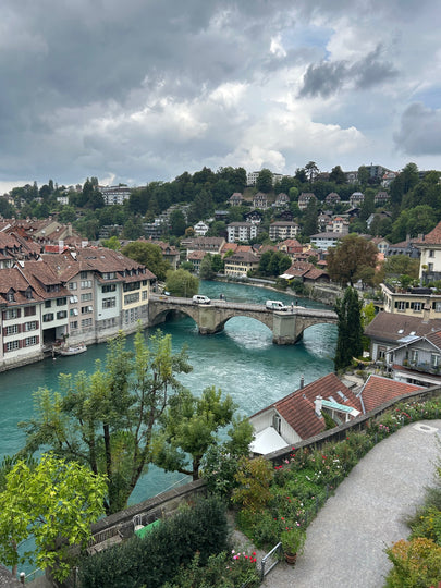 Aerial view of Bern and the turquoise  Aare river running through it, surrounded by greenery and buildings.