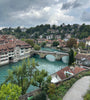 Aerial view of Bern and the turquoise  Aare river running through it, surrounded by greenery and buildings.