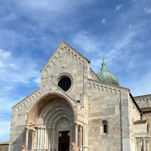 White stone facade of Cathedral of St. Cyriacus in Ancona Italy. The entrance is formed of a round arch with 4 columns