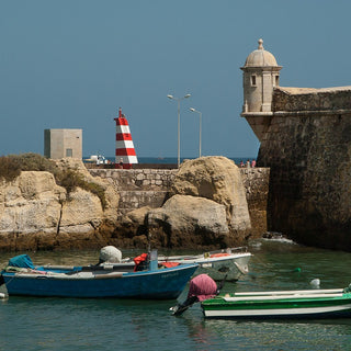 Harbour wall and two colourful small boats in Tavira Portugal