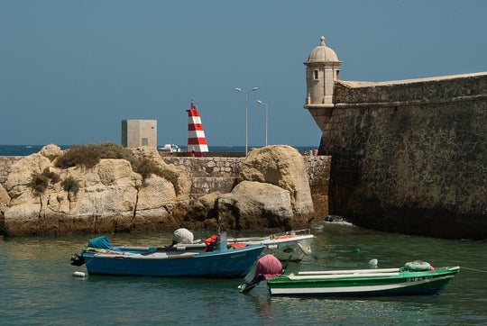 Harbour wall and two colourful small boats in Tavira Portugal