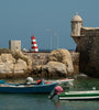 Harbour wall and two colourful small boats in Tavira Portugal