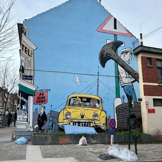 The side of a house with a cartoon style mural of a yellow car and a sailor holding an anchor in Brussels, Belgium
