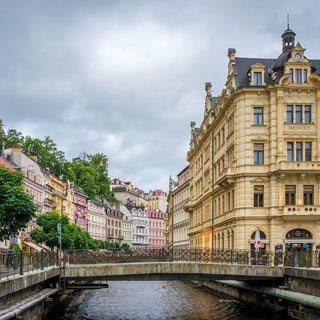 Karlovy Vary cityscape with historic buildings along a river under a cloudy sky