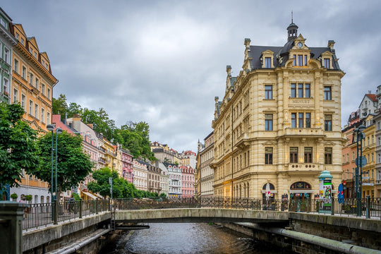 Karlovy Vary cityscape with historic buildings along a river under a cloudy sky