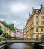 Karlovy Vary cityscape with historic buildings along a river under a cloudy sky