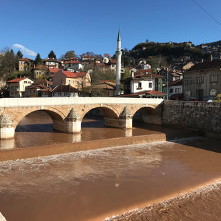 A four arched bridge crossing the chocolate coloured Milijacka river in Sarajevo