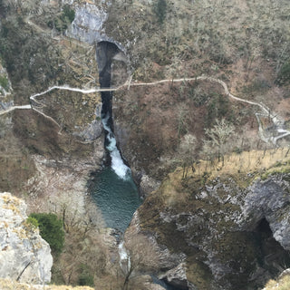 View into the gorge to Postojna Cave in Slovenia with waterfall and pool 
