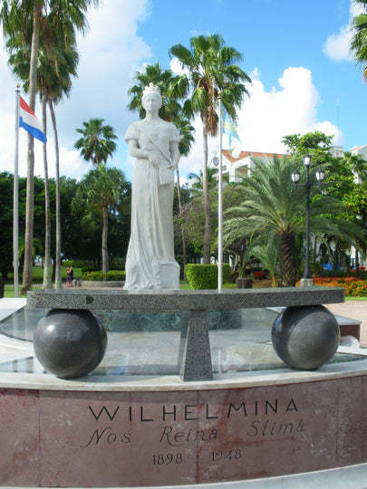 White marble statue of Queen Wilhelmina of the Netherlands, surrounded by a lush waterfront park