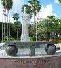 White marble statue of Queen Wilhelmina of the Netherlands, surrounded by a lush waterfront park