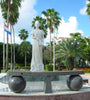 White marble statue of Queen Wilhelmina of the Netherlands, surrounded by a lush waterfront park