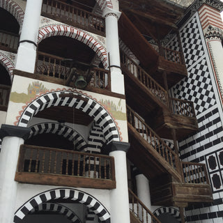 Wooden staircase of Rila Monastery and walls and arches decorated with black and white tiles. Bulgaria