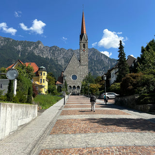 Pathway to Cathedral of St. Florin a neo-Gothic church in Vaduz, Liechtenstein.  Mountain and blue sky backdrop