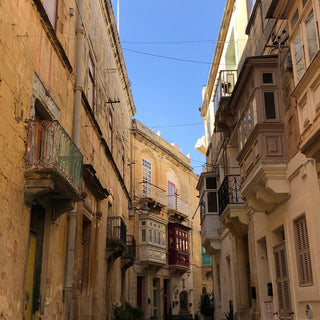 A narrow street in Valletta Malta with traditional yellow stone houses on both sides 