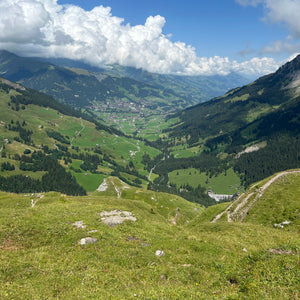 View of Alpine valley with blue sky and a white fluffy cloud near Adelboden, Switzerland 