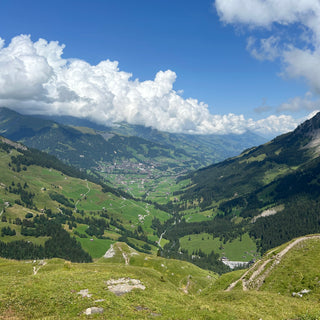 View of Alpine valley with blue sky and a white fluffy cloud near Adelboden, Switzerland 