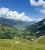 View of Alpine valley with blue sky and a white fluffy cloud near Adelboden, Switzerland 