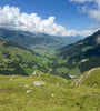 View of Alpine valley with blue sky and a white fluffy cloud near Adelboden, Switzerland 